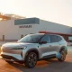 Rivian R2 SUV parked outside a modern EV factory at sunset