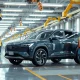 Rivian R2 SUV on an automated assembly line with robotic arms and engineers in a modern factory
