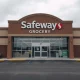 Closed Safeway grocery store with sign on door in a shopping center parking lot