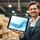 Professional holding tablet in a modern e-commerce fulfillment center, representing Shopify's AI-driven sales growth