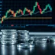 Silver bullion coins and bars on a trading desk with a monitor showing a declining price chart