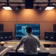 Audio engineer at a mixing console with AI waveforms on a screen in a modern studio