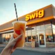 Customer receiving a colorful dirty soda at a Swig drive-thru storefront.