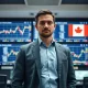 Financial analyst monitoring currency charts on trading floor screens with Swiss and Japanese flags visible