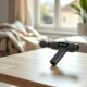 Theragun Sense massage gun with glowing LCD screen on a wooden table in a bright living room