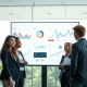Professionals in a modern office reviewing AI workflow dashboards on a large screen