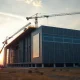 Construction site of a large AI data center with cranes and workers at dusk