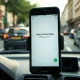 Smartphone on a car dashboard showing the Uber driver app, with a blurred city street background.