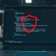 Laptop screen with code and shield icon representing the Windows zero-day vulnerability