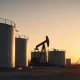Aerial view of oil storage tanks and pumpjack at a WTI crude facility at sunset