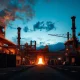 Aerial view of the ArcelorMittal steel production facility at dusk with molten metal glowing.