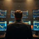 Trader at a multi-monitor desk watching cryptocurrency price charts at night