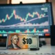 Canadian and US dollar banknotes on a desk with a currency chart in the background