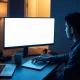 Person at a dimly lit desk looking at two open laptops showing a checkbox page