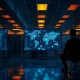 A dimly lit cybersecurity lab with an analyst watching a network diagram on a large monitor