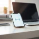 Smartphone and laptop displaying Google's voice AI interface in a bright office setting