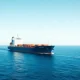 A large cargo ship with a hydrogen injection system retrofit sails on calm ocean waters.