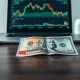 Indonesian rupiah and US dollar banknotes on a desk with a financial chart in the background