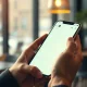 Hands holding a smartphone showing a digital assistant chat interface in a coffee shop