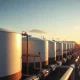 Natural gas storage tanks and pipes at an industrial facility at sunset