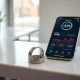Oura smart ring beside a smartphone showing health tracking data on a desk