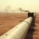 Damaged Saudi East-West pipeline pump station in desert with smoke rising near Red Sea terminal