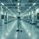 Workers in protective suits operating semiconductor equipment inside a chip fabrication cleanroom